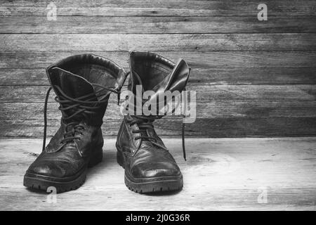 Vieux cuir noir hommes chaussures cheville bottes sur fond en bois vue de face gros plan avec espace pour votre texte, noir et blanc photo Banque D'Images