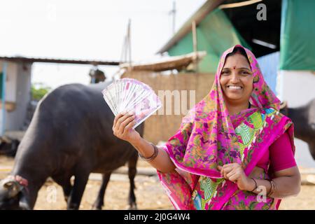 Concentrez-vous sur les billets de monnaie, souriant lait lait village femmes montrant l'argent indien en regardant la caméra - concept de profit d'affaires, les banques et Banque D'Images