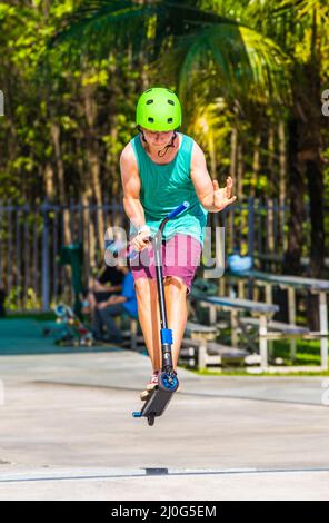 Teenage boy a fun riding push son scooter à la skate park Banque D'Images