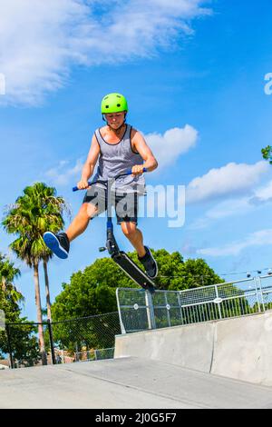 Teenage boy a fun riding push son scooter à la skate park Banque D'Images