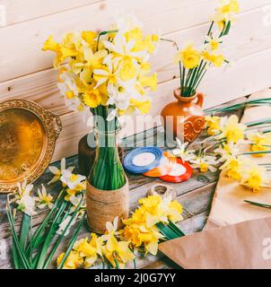 Bouquets de jonquilles jaunes fleurs dans un vase et un pichet de papier Kraft et rubans colorés avec une queue de corde sur un bois Banque D'Images