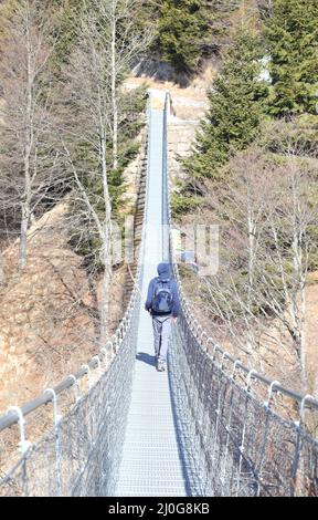 L'homme marche sur le pont suspendu en acier inoxydable dans le nord de l'Italie Banque D'Images