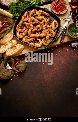 Crevettes grillées dans une poêle en fonte avec citron frais, persil, piment, sauce au vin blanc à l'ail Banque D'Images