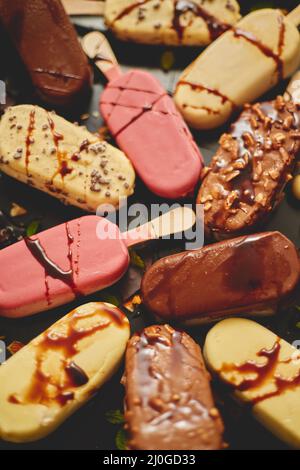 Crème glacée sur bâton recouverte de divers glaçures de chocolat et garnitures. Vue de dessus, plan d'appartement Banque D'Images