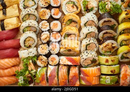 Vue de dessus de l'arrière-plan avec ensemble de différentes couleurs de petits pains à sushis placés sur un panneau en bois Banque D'Images