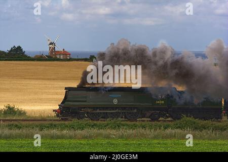 Locomotive à vapeur 34081 92 escadron passant par le moulin à vent de Weybourne, chemin de fer de North Norfolk. Banque D'Images