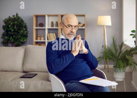 Portrait d'un psychologue homme principal professionnel assis dans son bureau et en attente d'un patient. Banque D'Images