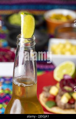 Lime dans une bière avec tortilla mexicaine et salsas Banque D'Images
