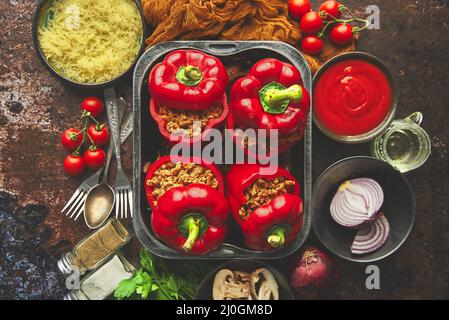 Poivrons paprika farcis à la cloche rouge dans un pot de cuisson en fer avec divers ingrédients sur le côté Banque D'Images