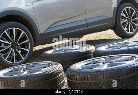 Roues d'hiver lavées devant une voiture moderne avec roues d'été Banque D'Images