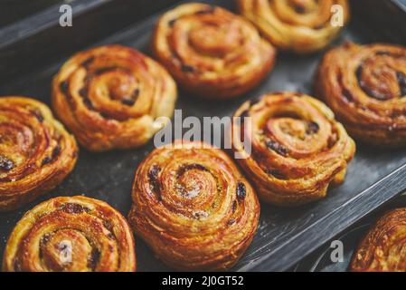 Feuilleté maison aux petits pains à la cannelle et aux raisins secs placés au four fer à repasser Banque D'Images