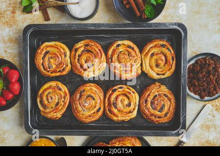 Petits pains à la cannelle frais sur plateau en fer noir. Vue sur le dessus Banque D'Images
