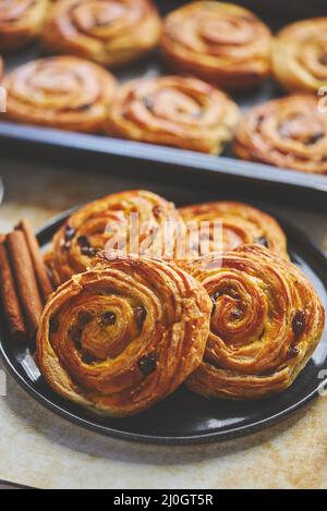 Délicieux petits pains à la cannelle frais servis sur une assiette en céramique noire. Avec différents côtés Banque D'Images