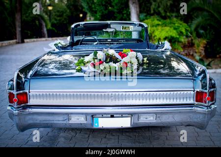 Une voiture lors d'un mariage, décorée d'un bouquet, dans un parking en soirée. Banque D'Images