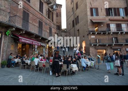 Les gens se détendent dans les cafés des rues de la ville historique de Sienne, Italie, Europe Banque D'Images