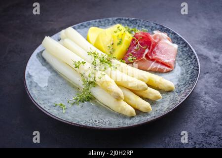 Asperges blanches traditionnelles cuites à la vapeur avec du jambon fumé et des pommes de terre cuites garnies de sauce au beurre, servies en gros plan sur un Nordi Banque D'Images