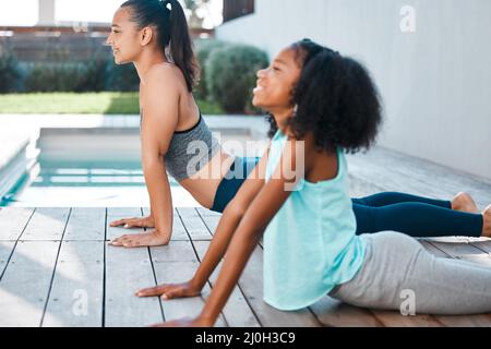 Le yoga nous aide à nous détendre. Photo d'une jeune mère et d'une fille pratiquant le yoga à l'extérieur. Banque D'Images