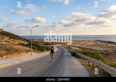 Randonnée Backpacker sur l'île de Chypre, homme avec des promenades à dos le long de l'autoroute sur la colline près de la mer Méditerranée à Agios Geor Banque D'Images