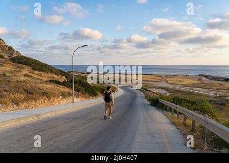 Des randonneurs mâles sur une route de montagne en asphalte surplombant la mer à Chypre près d'Agios Georgios Pegeias. Route menant à ba Banque D'Images