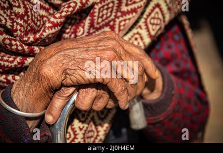 Gros plan sur les mains froissées croisées d'une grand-mère népalaise aînée. Banque D'Images