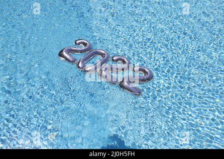 Des chiffres argentés flottent sur de l'eau de piscine bleue propre, décor festif Banque D'Images