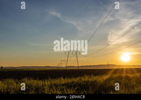 Tours de transmission électrique haute tension et lignes électriques au coucher du soleil. Banque D'Images