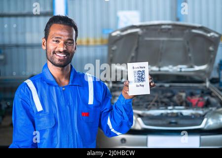 car mécanicien montrant scanner ici pour payer le tableau de code qr pour le paiement par la recherche de caméra - concept de paiement numérique, technologie et transaction sans espèces Banque D'Images