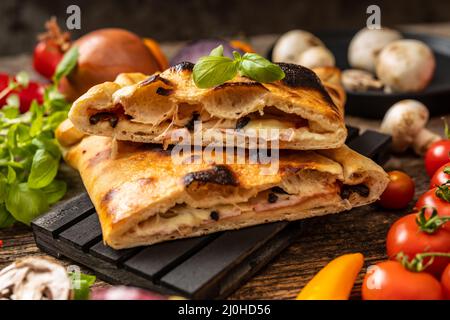 Pizza en tranches calzone servie sur une palette noire Banque D'Images