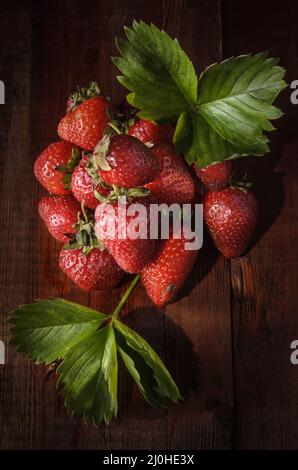 Baies de fraises mûres sur fond de bois sombre dans un style rustique Banque D'Images