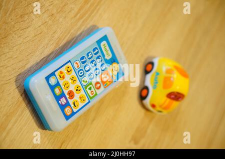 Téléphone jouet de marque Fisher-Price à côté d'une voiture V Tech avec des sons sur une languette en bois Banque D'Images