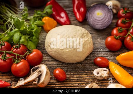 Une délicieuse pâte à pizza crue avec de nombreux légumes servis sur du noir Banque D'Images