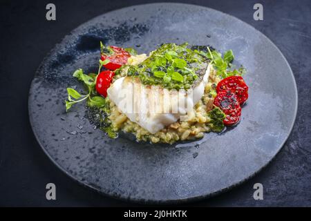 Filet de cabillaud frit traditionnel de style moderne avec risotto au riz aux champignons et relish à la salsa d'origan servi en gros plan sur un Banque D'Images