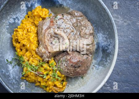 Style moderne traditionnel italien braisé ossobuco alla milanais avec risotto au safran et bébé brocoli dans une sauce à la viande au vin blanc Banque D'Images