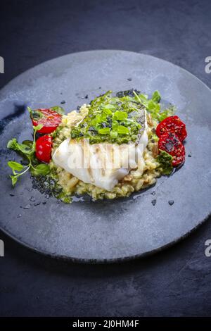 Filet de cabillaud frit traditionnel de style moderne avec risotto au riz aux champignons et relish à la salsa d'origan servi en gros plan sur un Banque D'Images