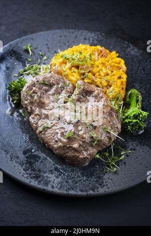 Style moderne traditionnel italien braisé ossobuco alla milanais avec risotto au safran et bébé brocoli dans une sauce à la viande au vin blanc Banque D'Images