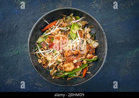 Curry traditionnel thaïlandais de style moderne avec crevettes géantes et nouilles au barbecue, vue imprenable sur un bol de style nordique avec copie Banque D'Images