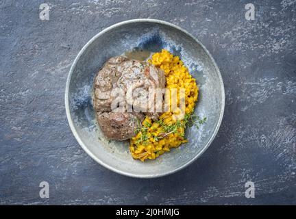 Style moderne traditionnel italien braisé ossobuco alla milanais avec risotto au safran et bébé brocoli dans une sauce à la viande au vin blanc Banque D'Images