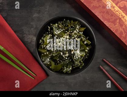 Salade d'algues wakame. Bol et bâtonnets de bambou. Cuisine orientale. Vue de dessus. Banque D'Images