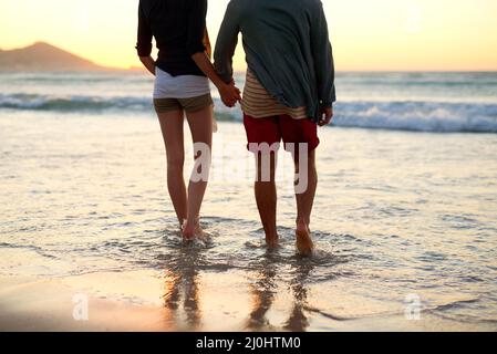Des chroniques romantiques sur le bord de mer. Vue arrière d'un couple méconnaissable en marchant vers la plage. Banque D'Images