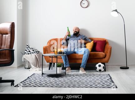 Drôle paresseux homme de boire de la bière et regarder le football à la maison Banque D'Images
