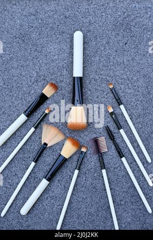 gros plan sur le faisceau blanc brun kit de maquillage brossez sur fond gris brun non focus. Banque D'Images