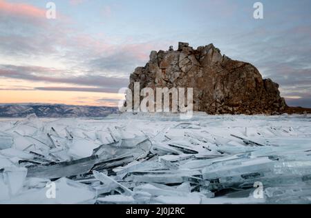 La falaise de Shamanka sur le lac Baikal, en Russie, avec des brisures de glace en premier plan et des touristes en haut Banque D'Images