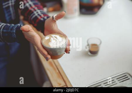 Photo en gros plan des mains de la femme tenant une tasse de cappuccino Banque D'Images