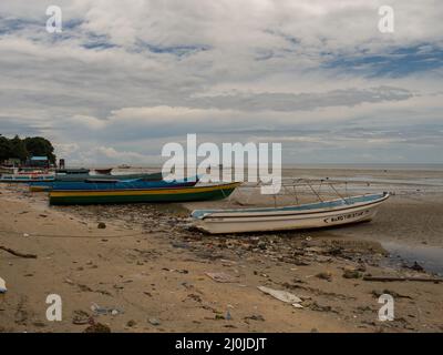 Kaimana, Arguni Bay, Indonésie - février 2018 : problème de pollution. Bateaux en bois et plein de déchets sur la plage à marée basse au port d'un petit Banque D'Images