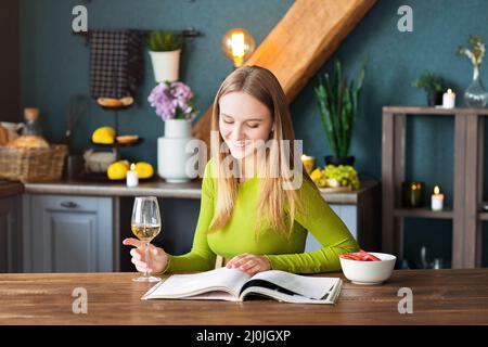 Jeune femme lisant un magazine intéressant à table en bois Banque D'Images