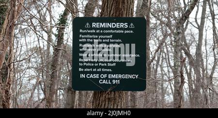 Un panneau d'avertissement rappelant aux gens d'être au courant des environs affiché sur un arbre sur un sentier de marche en cours dans les bois. Banque D'Images