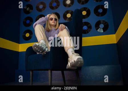 portrait d'une jeune fille élégante sur une chaise bleue. Banque D'Images