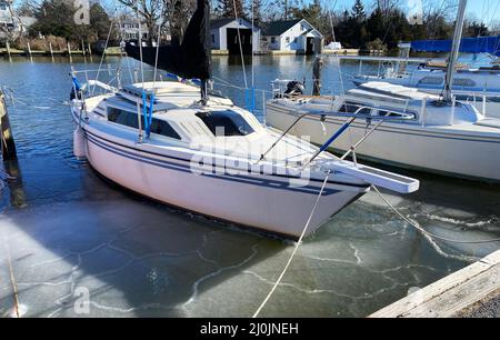Les voiliers se sont attachés à un quai à Babylone, New York, long Island, avec de la glace formant autour des bateaux en février. Banque D'Images
