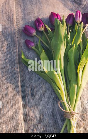 Plan vertical d'un bouquet de tulipes violettes sur du bois de grève Banque D'Images