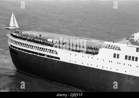 QE2 revient à Southampton. Les Union Jacks sont festoonés sur les voitures, drapés sur les épaules, ondulés sur des bâtons. Southampton donne un accueil « Three Cheers » au paquebot de luxe QE2 devenu trooper de retour de la guerre. À bord se trouve sa précieuse cargaison, les 700 survivants du HMS Coventry, ardent et antilope, qui ont sombré dans la bataille pour les Malouines. 11th juin 1982. Banque D'Images